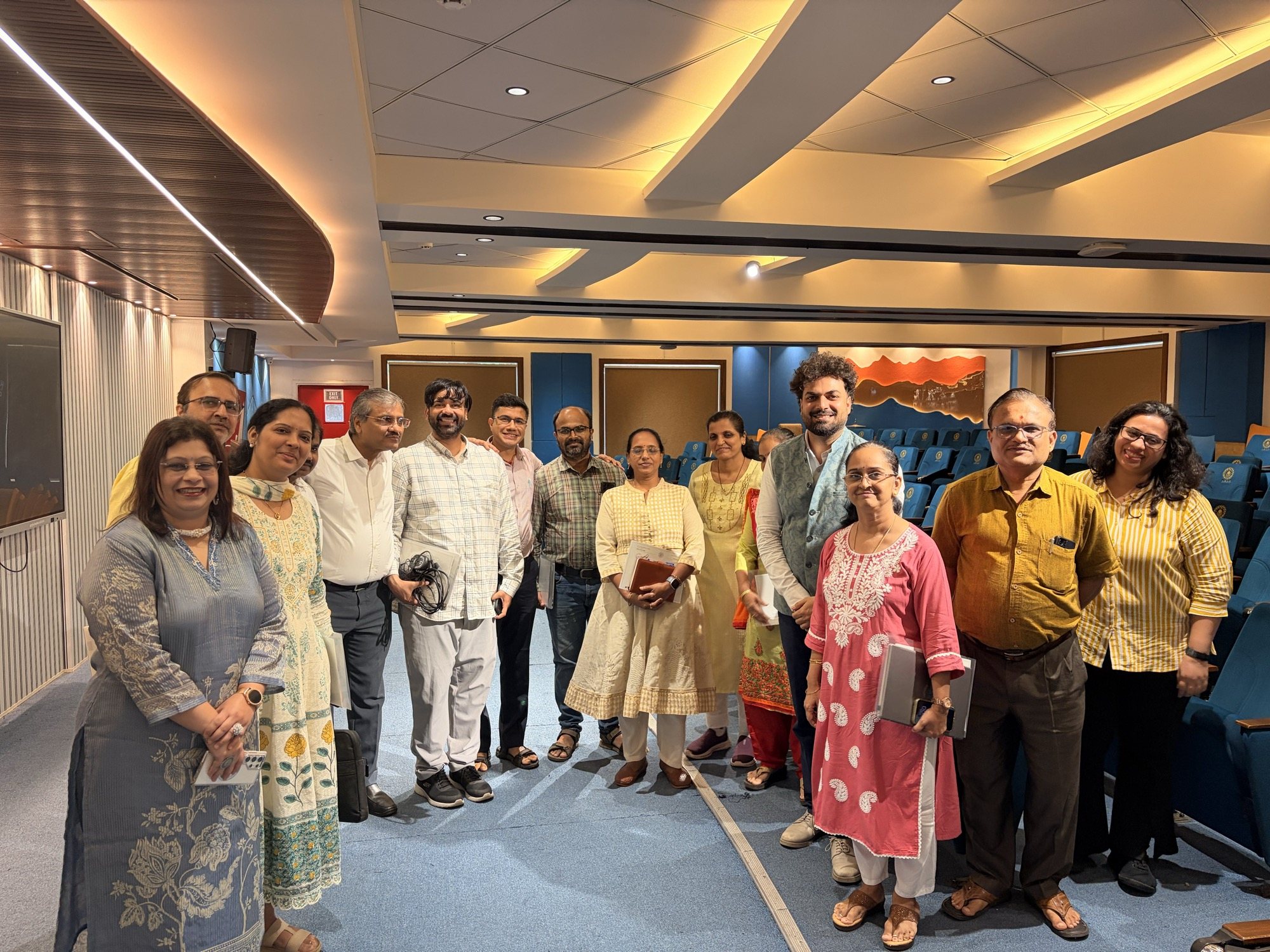 The S.P.I.T. faculty cohort standing together in the auditorium with Ashish Tripathi